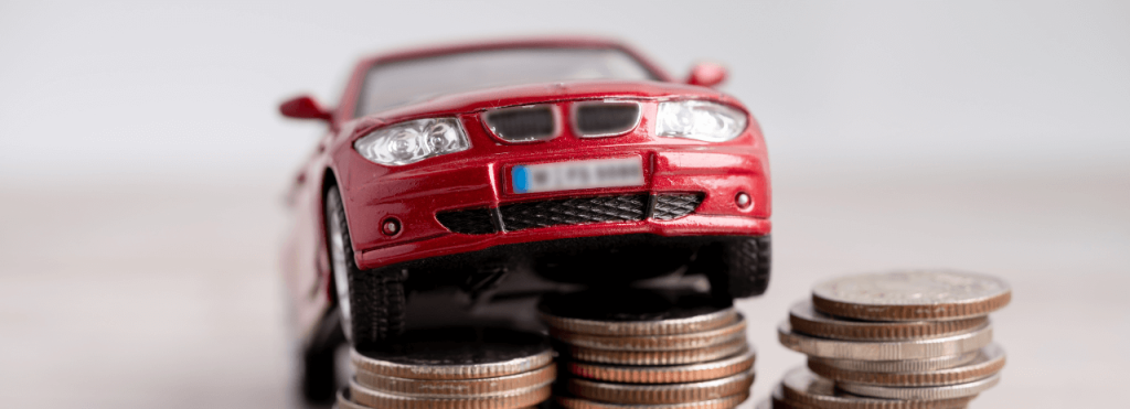 Petite voiture posée sur des piles de pièces pour comparer crédit auto, LOA et LLD