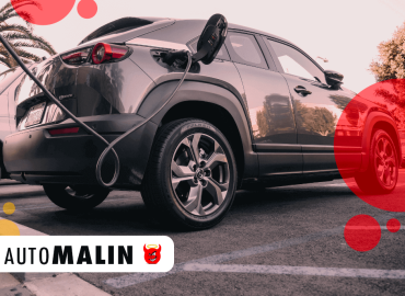 Voiture électrique grise en train de se recharger sur une borne dans un parking