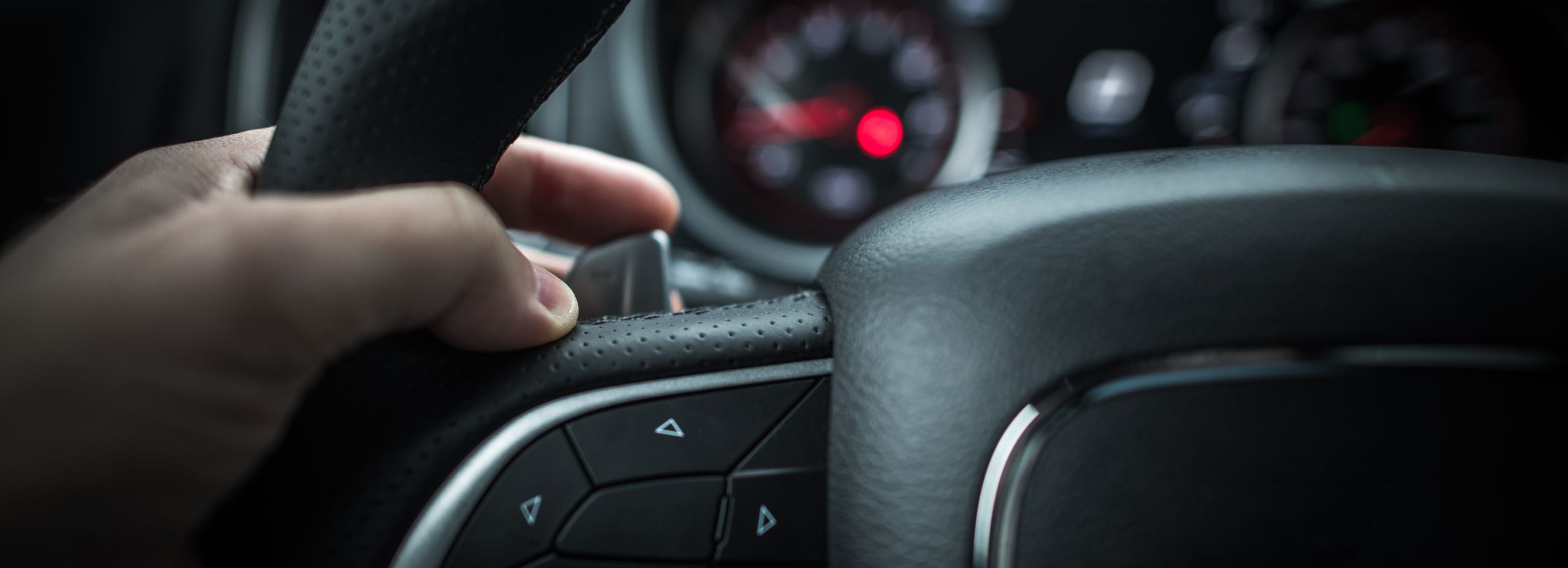 Main d'un conducteur actionnant une palette au volant d'une voiture à boîte séquentielle.