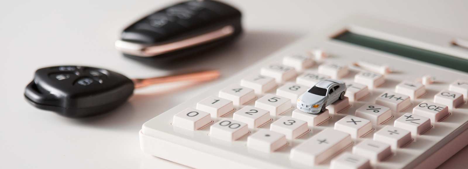 Calcul du coût d'assurance auto avec. voiture miniature et clés de voiture sur calculatrice.
